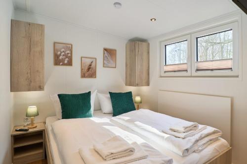 a bedroom with a bed with white sheets and green pillows at Ostseecamp Haus Im Eck 142 mit kostenfreier Saunanutzung in Scharbeutz