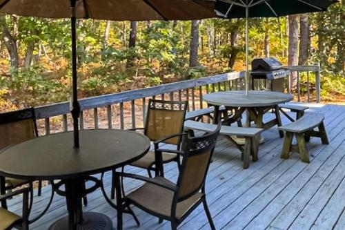 two tables and chairs with umbrellas on a deck at Serene Cape Escape in Wellfleet