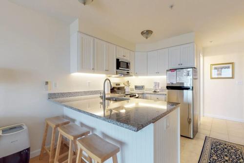 a kitchen with a sink and a counter with stools at Bayside Beauty in Truro