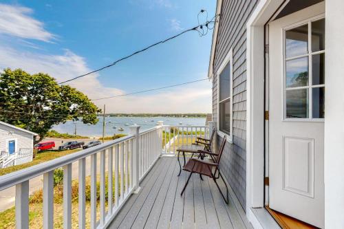 a porch with a bench and a door with a view of the water at Bella Luna in Falmouth