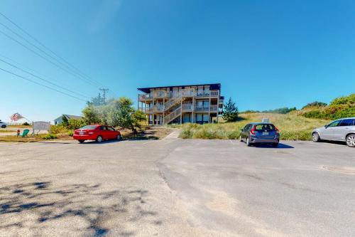 a parking lot with cars parked in front of a building at Sand & Beach Within Reach in North Truro