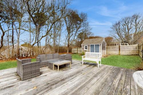 a backyard with a wooden deck with a bench and a table at Lucky Number Seven in Chatham
