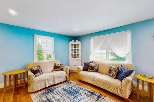 a living room with two white couches and blue walls at Winthrop Cottage in Oak Bluffs
