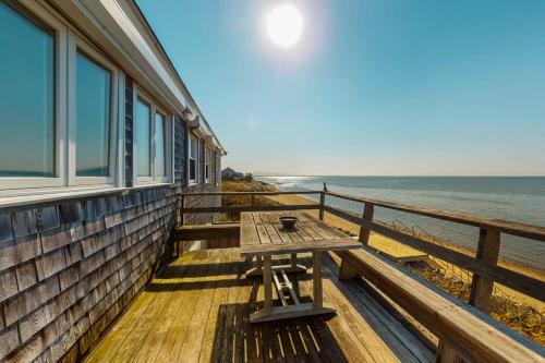 a picnic table on the porch of a house overlooking the ocean at Beaches n' Sunsets in Eastham