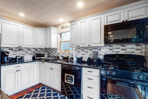 a kitchen with white cabinets and black appliances at Brewster House in Oak Bluffs