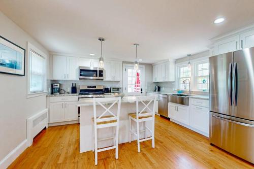 a kitchen with white cabinets and a stainless steel refrigerator at Ocean Bird Nest in South Yarmouth