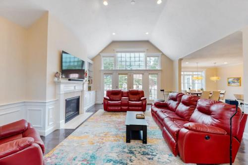 a living room with red leather furniture and a fireplace at Cape Castle in Mashpee