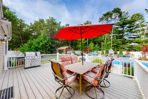 a wooden deck with a table with a red umbrella at Cape Castle in Mashpee