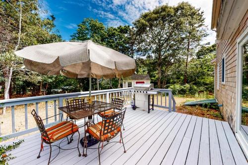 a patio with a table and chairs and an umbrella at Dream Dennis Getaway in Dennis