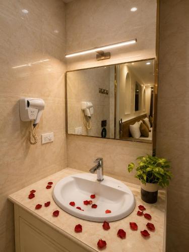 a bathroom with a sink with red roses on the counter at Majestik Hanoi Hotel in Hanoi