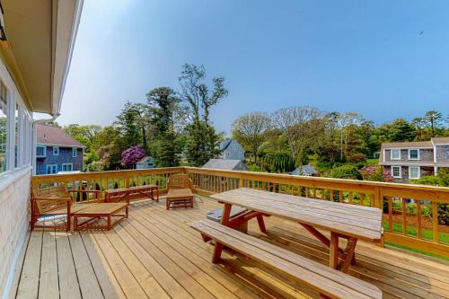 a wooden deck with benches and tables on it at New England Getaway in Dennis