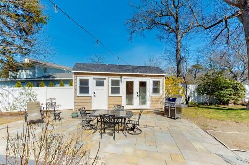 a patio with a table and chairs and a house at Adventures on Buzzards Bay in Bourne