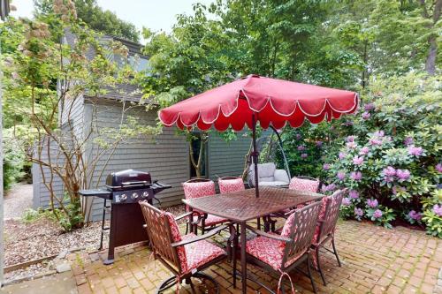 a table and chairs with an umbrella and a grill at South Cape Escape in Mashpee