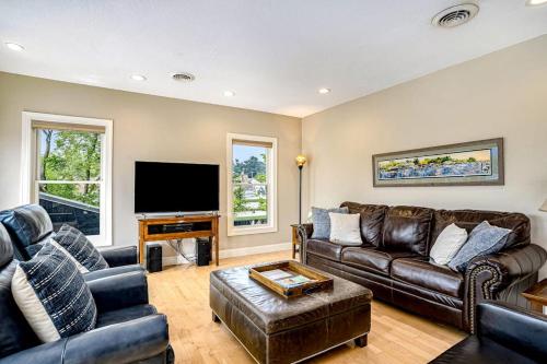 a living room with leather furniture and a flat screen tv at Lake View Getaway in Saugatuck