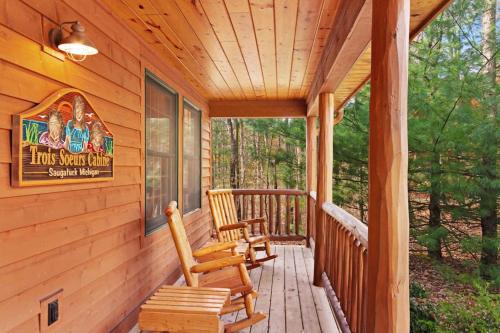 a porch of a log cabin with two rocking chairs at Kingfisher Cove Cabin 28 in Saugatuck