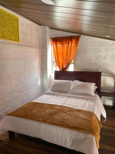 a bedroom with a large bed with an orange curtain at Cabañas San Carlos - Puembo Centro in Puembo