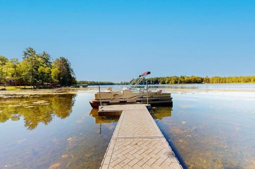 a dock on a lake with a boat in the water at Chalet on the Bay in Saint Germain