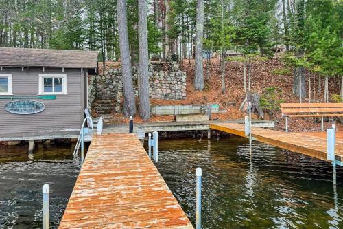 a dock with a house and a bench on the water at Moon Ridge Lodge in Saint Germain
