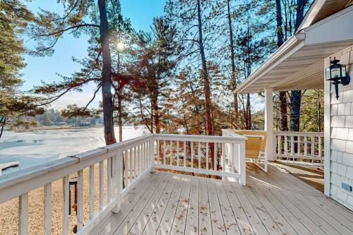 a white house with a wooden porch with trees at Yellow Birch Memories in Eagle River