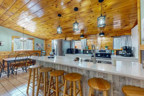 a large kitchen with wooden ceilings and a bar with stools at Roaming Deer Cottage in Saint Germain
