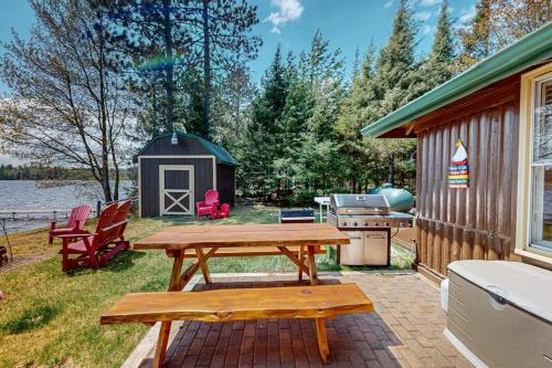 a picnic table in front of a cabin with a grill at The View on Found Lake in Saint Germain