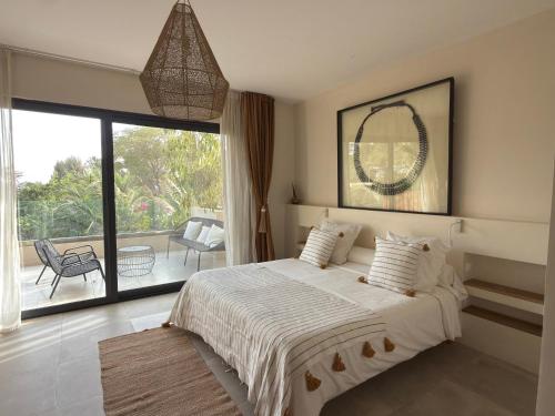 a bedroom with a large bed and a balcony at Villa YEMAYA - Villa d'hôtes in Ngaparou