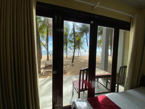 a bedroom with a view of the beach from a door at Beachfront Bungalow Cuu Long in Phú Quốc