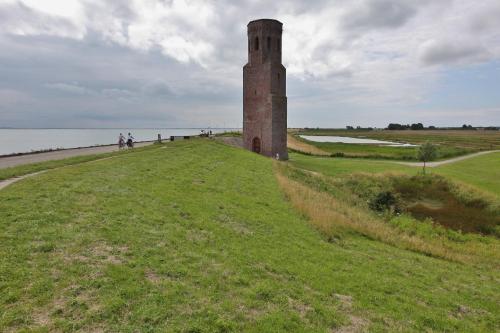 a tower in a field next to a body of water at Resort Land & Zee in Scharendijke