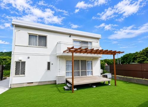 a white house with a pergola on a lawn at Itoshima STAY YAMAGA Keya in Itoshima