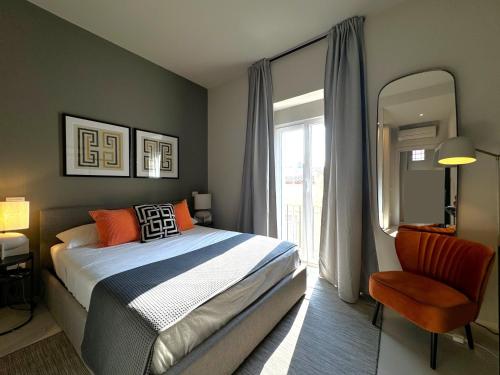 a bedroom with a bed and a chair and a window at Casa Lumae in Noto