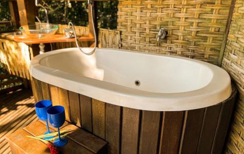 a bath tub with two blue glasses and a table at Paraty Paradiso in Parati-Mirim
