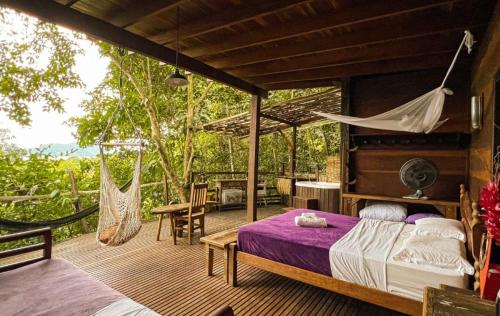 a bedroom with a bed and a hammock on a deck at Paraty Paradiso in Parati-Mirim