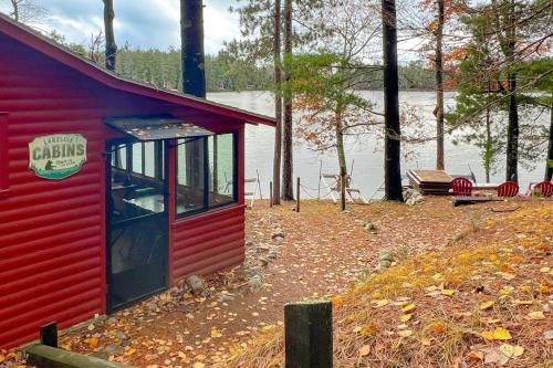 a red building next to a body of water at Little Red Lakeside Cabin in Three Lakes