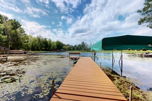 a dock on a lake with a green tent at Tall Pines in Woodruff
