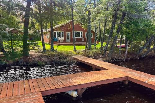 a wooden bridge over a pond in front of a house at Watermelon Retreat & Suite in Three Lakes