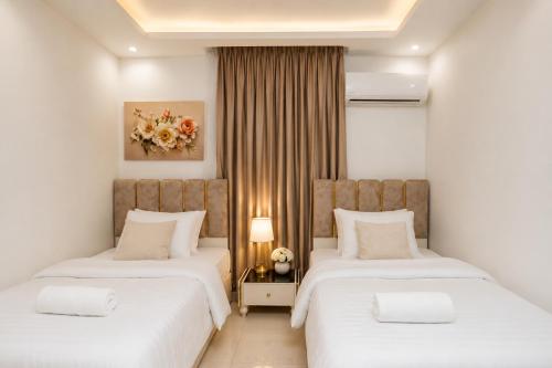 two beds in a hotel room with white walls at Luxurious Beachfront Apartment in Alexandria