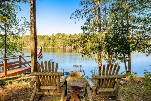 two chairs sitting next to a lake with an american flag at Northwoods Paradise in Eagle River