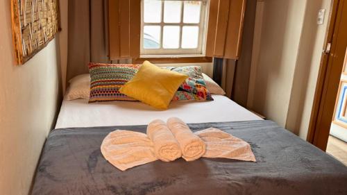 a bed with two towels on it with a window at Hospedagem Rancho Fundo in Diamantina