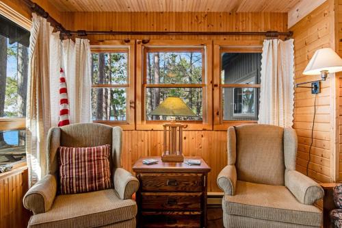 two chairs and a table in a room with windows at Bucky's PineIsle Retreat in Three Lakes