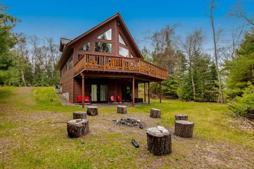 a large wooden house with a deck and some logs at Sandy Cove in Saint Germain