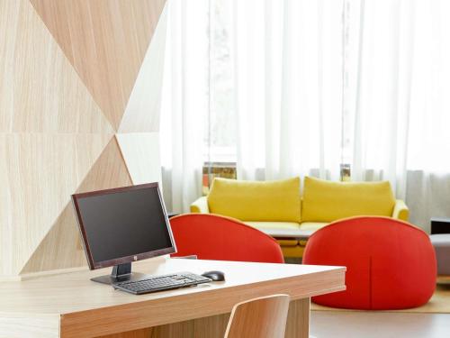 a desk with a computer and two red chairs at ibis Styles Makkah in Mecca
