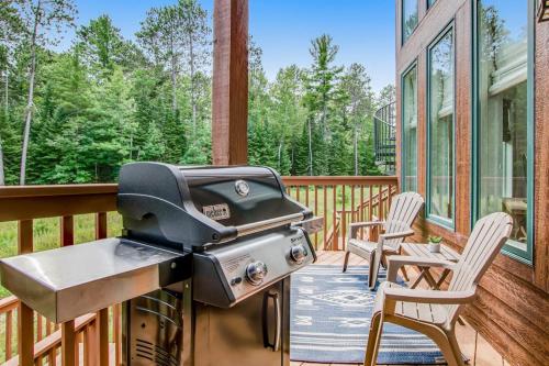 a grill on a deck with two chairs on a porch at Copperwood #4 in Eagle River
