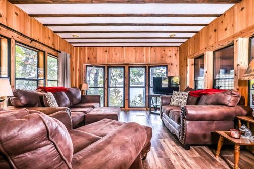 a living room with brown leather furniture and windows at Tranquility Base in Rhinelander