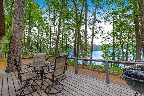 a deck with two chairs and a table and a grill at Our Lakeside Legacy in Saint Germain