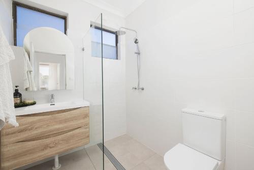 a white bathroom with a shower and a sink at Coastal Bliss in Lemon Tree Passage