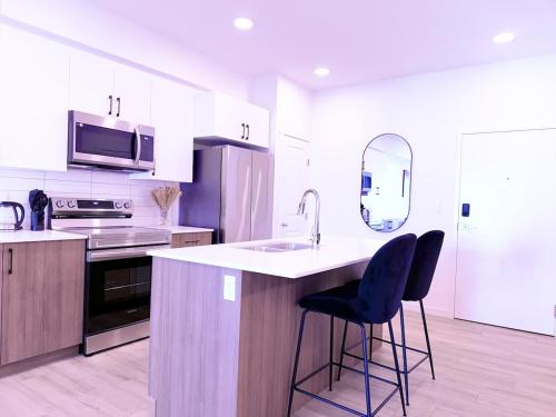 una cucina con un lavello e due sgabelli da bar di Condo in Secord a Edmonton