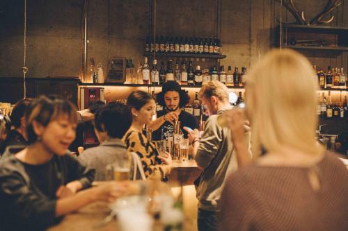 a group of people sitting at a bar at Nui. HOSTEL & BAR LOUNGE in Tokyo