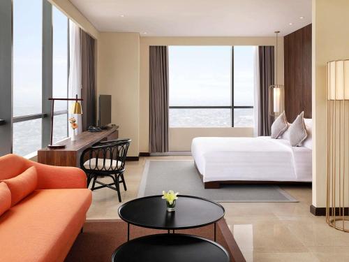 a hotel room with a bed and a desk at Novotel Samator Surabaya Timur in Surabaya