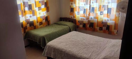 a room with two beds and a window with colorful curtains at Casa para 10 personas A 10 MIN CENTRO DE ORIZABA in Orizaba