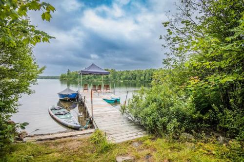 a dock with three boats on a lake at Le Chaleureux du Lac Blanc - Nominingue in Nominingue
